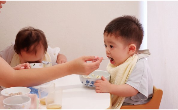 先生に支えられながら食べる子ども